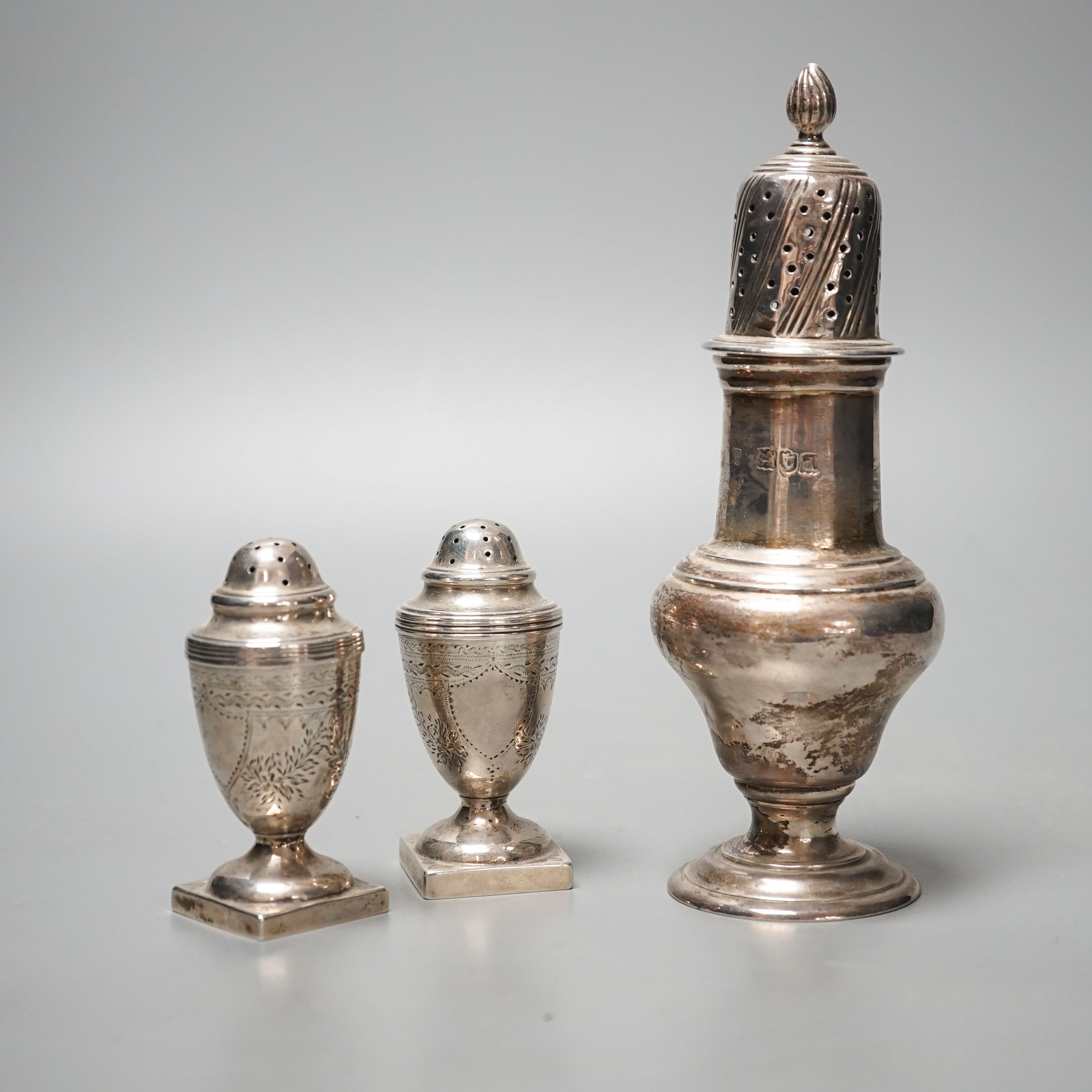 A late Victorian silver sugar caster, Charles Stuart Harris, London, 1899, 17cm and two silver early 20th century silver pepperettes, 7.5oz.